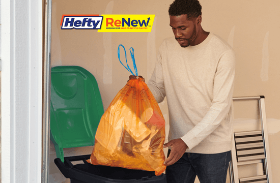 a man places an orange bag into his green-lid recycling cart