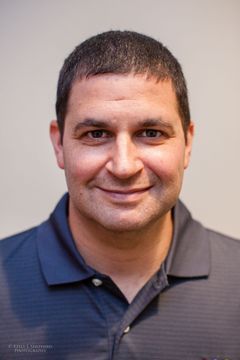 Board member Stuart Barnett smiles at the camera, wearing a blue polo shirt