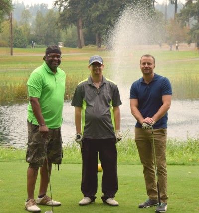 Reggie, Preston, and Scott pose in front of fountain with golf clubs