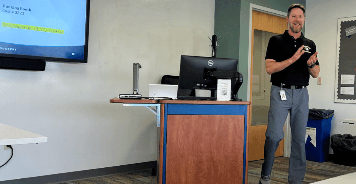 Man standing in a classroom next to a TV monitor