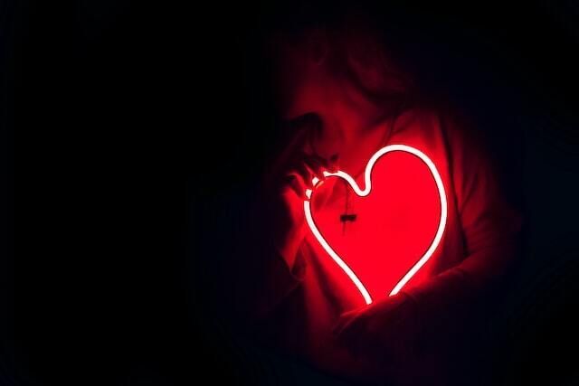 Indistinct person holding a neon light in the shape of a red heart