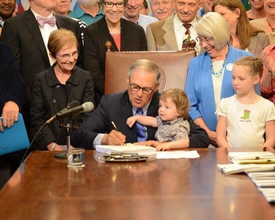 Justice Bridge watching as Governor Inslee signs the legislation for the new Children's Department.