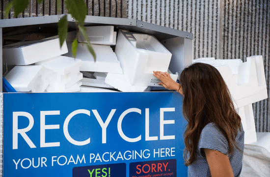 a woman places a rigid foam insert into a large container for Styrofoam recycling