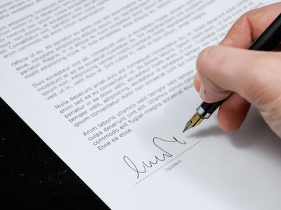 Close-up of a customer signing a printed business form.