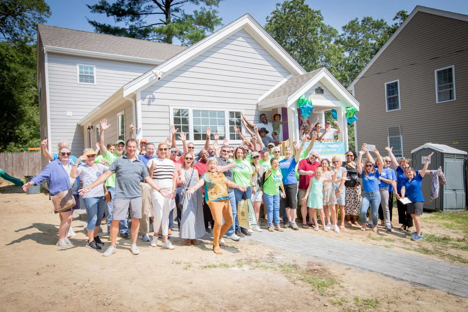 A large group of people celebrating in front of the new Habitat home