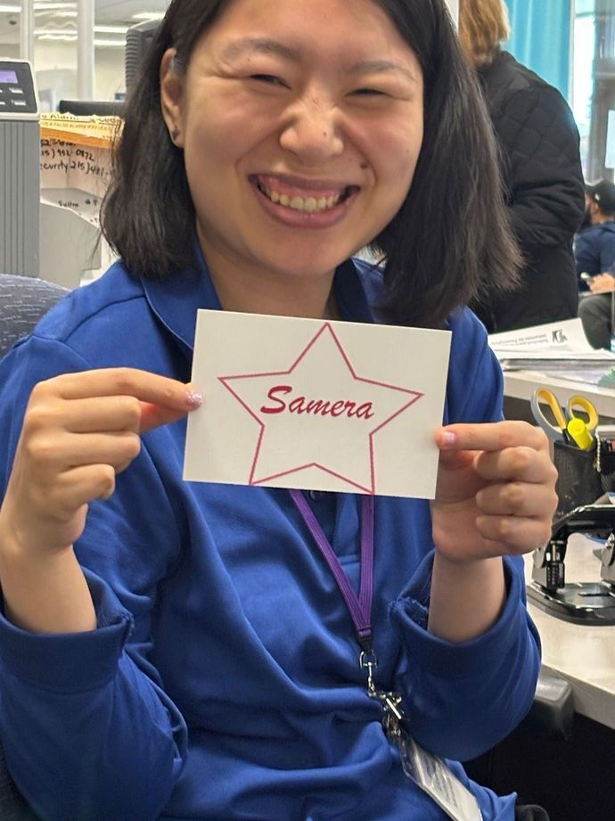 Miranda smiling in a blue PennDOT uniform holding a piece of paper that has star on it saying Samera.