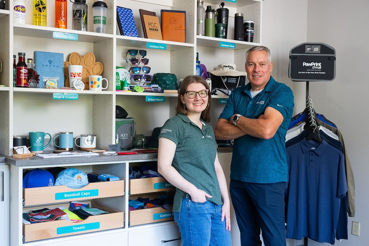 Woman and man standing in front of a shelf displaying promotional products