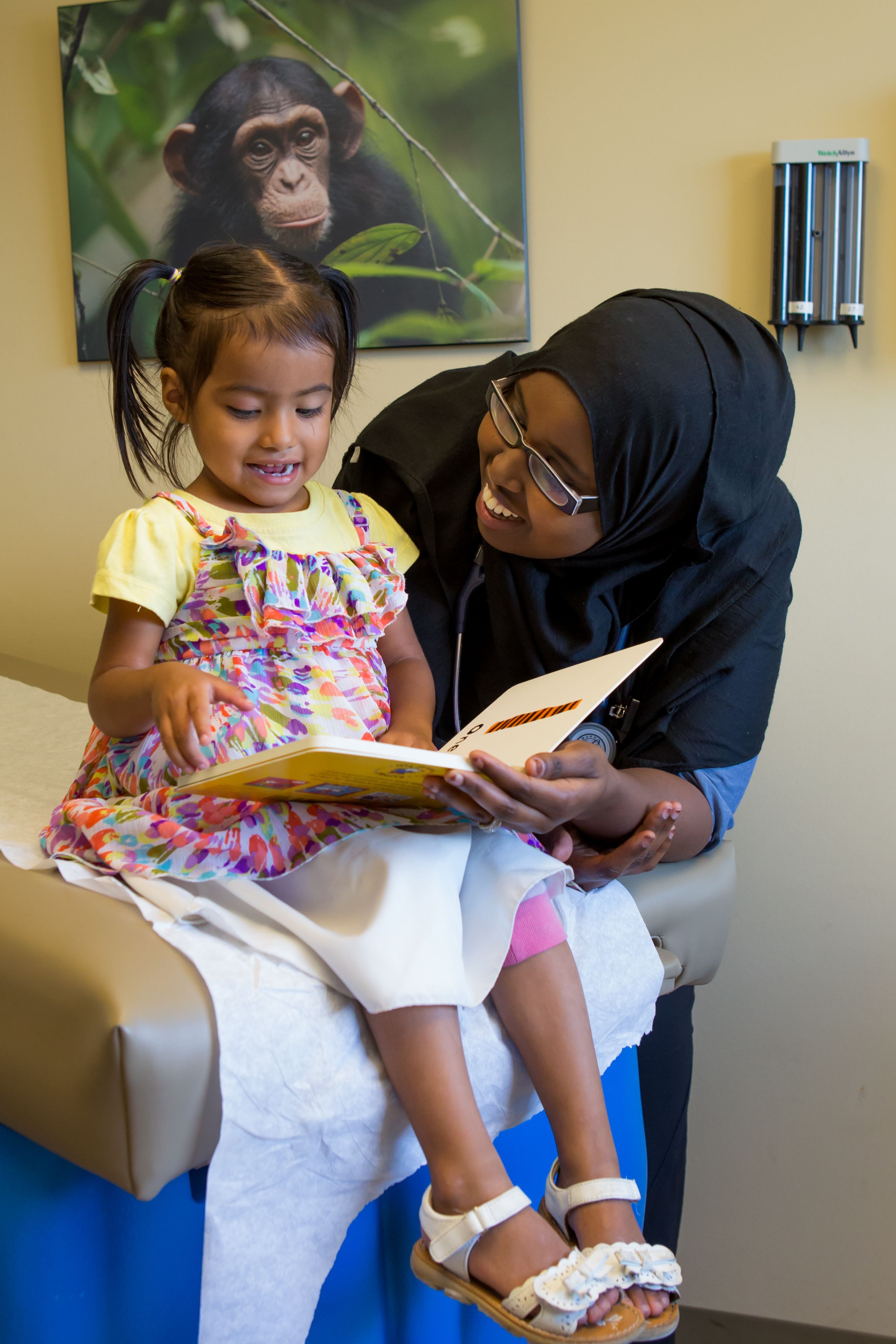 Mother, doctor, and boy smile at book together