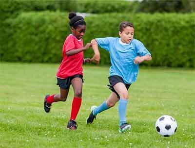 Kids playing soccer; girl chasing boy with soccer ball