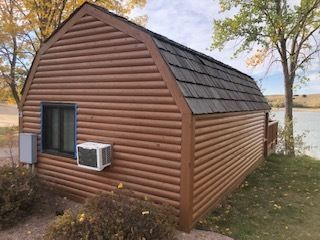 A brown cabin on a lake in South Dakota, freshly painted with wood stain.