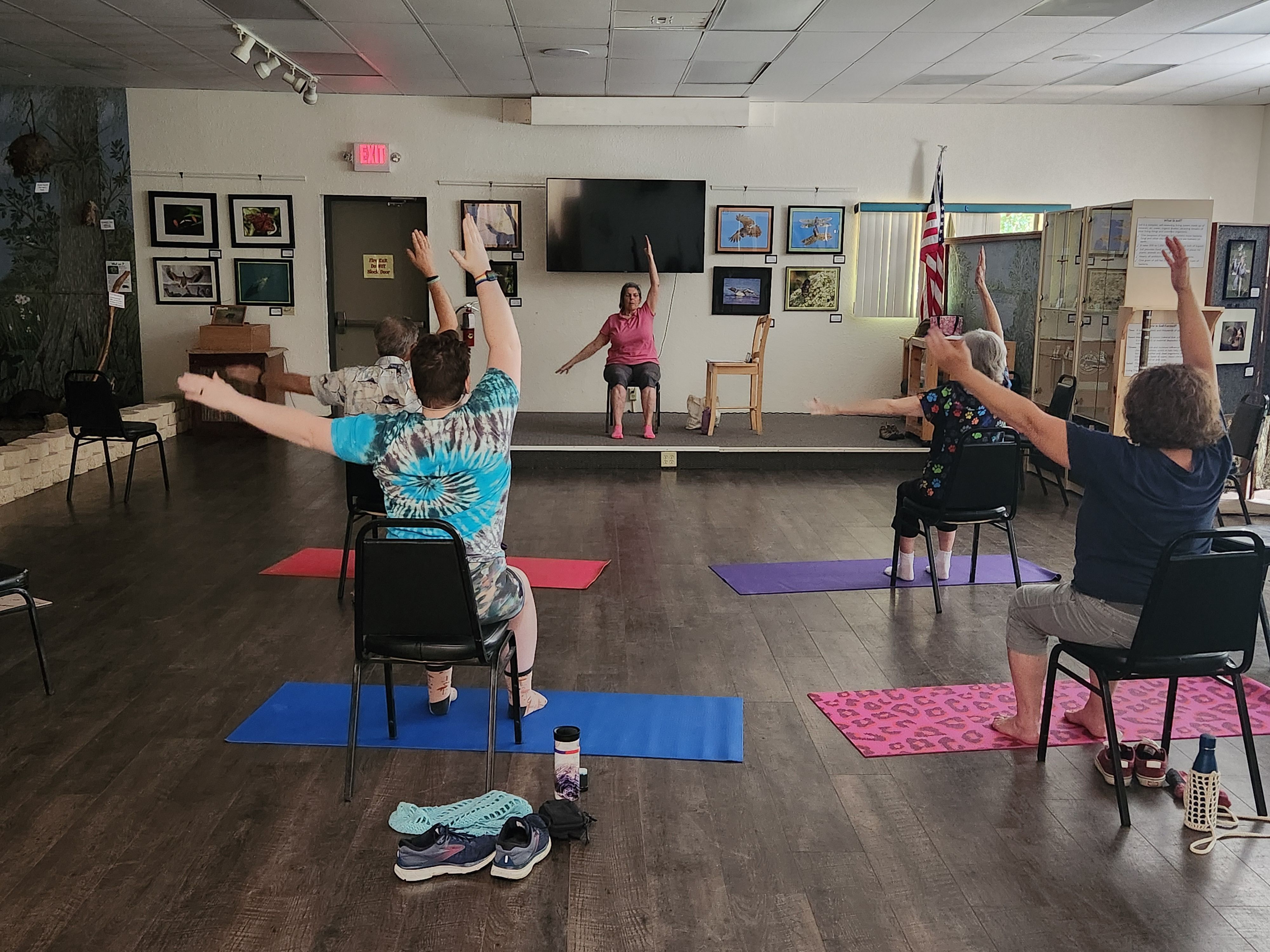 Yoga participants doing a yoga position using chairs or the floor.