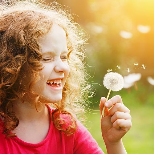 Happy young girl holding a dandelion