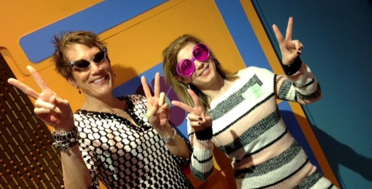 Two women wearing 1960s style sunglasses at the Smoky Hill Museum. The women are showing "peace" signs with their hands.