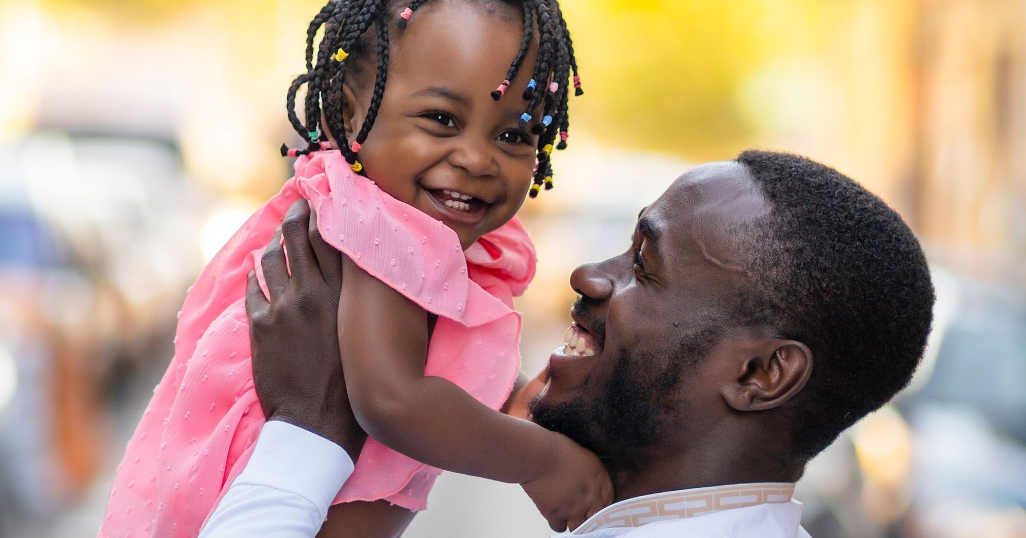 aftrican american man lifting a smiling african american baby girl