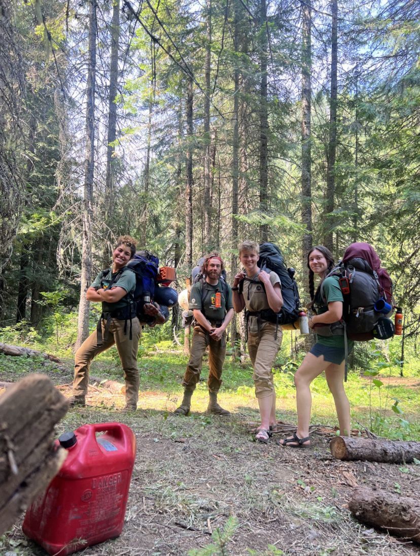 Crew members pose happily, holding gear and backpacks.