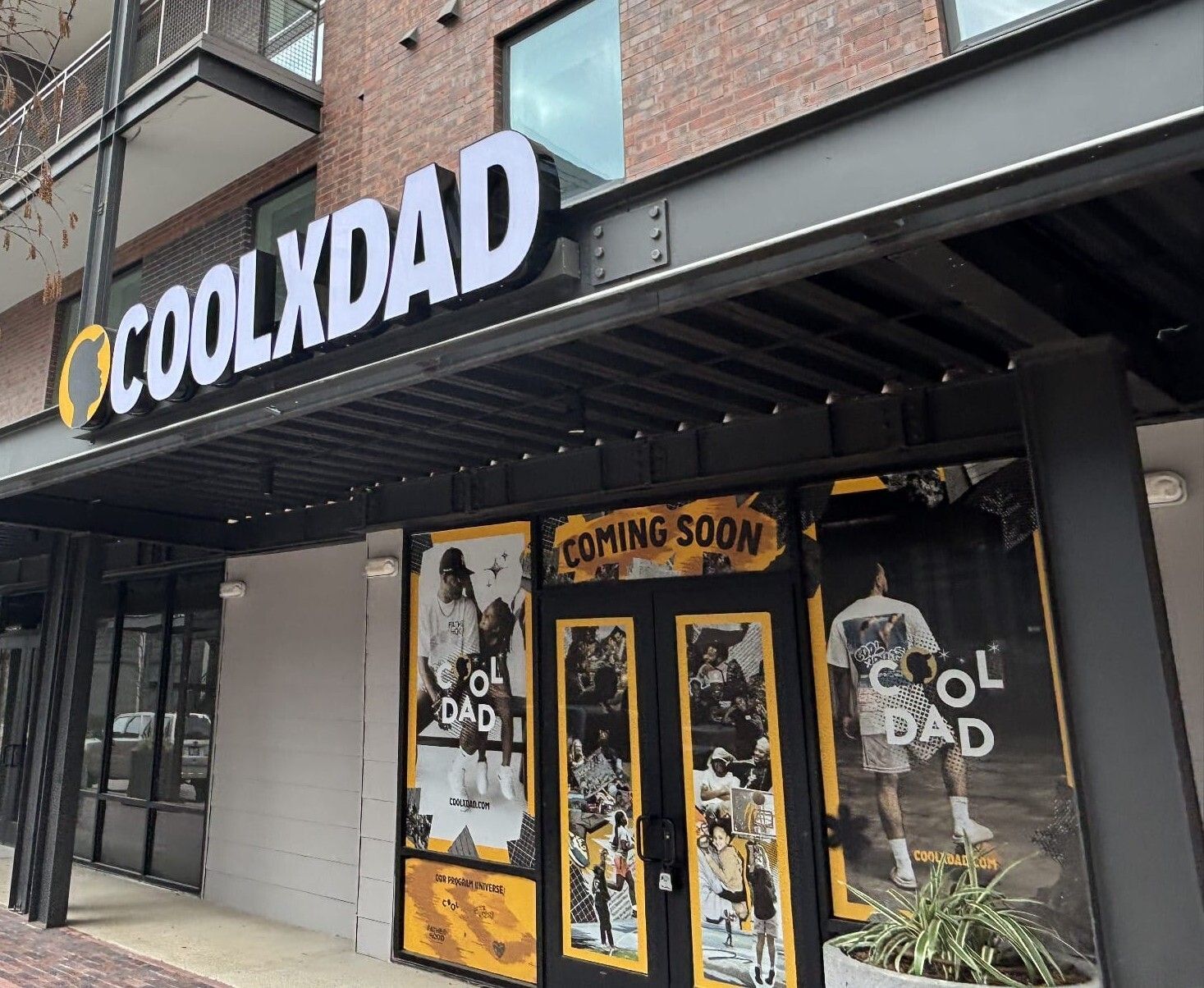 A retail storefront featuring bold, illuminated channel letter signage above the entrance and full-color window perf graphics on the lower windows, blending brand visibility with privacy.