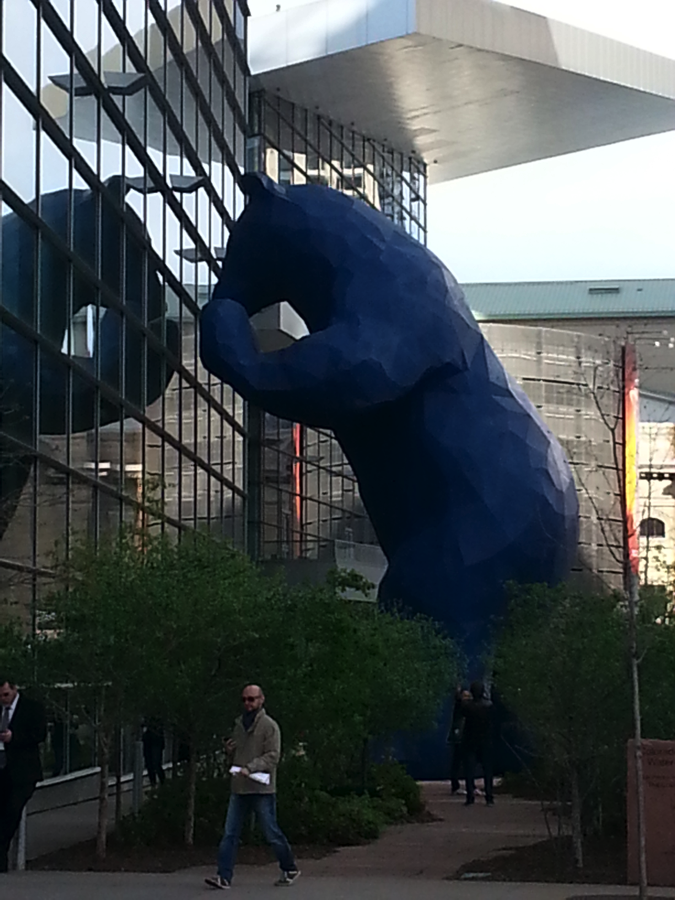 A picture of a 40-foot-tall Blue Bear sculpture peeking into a window