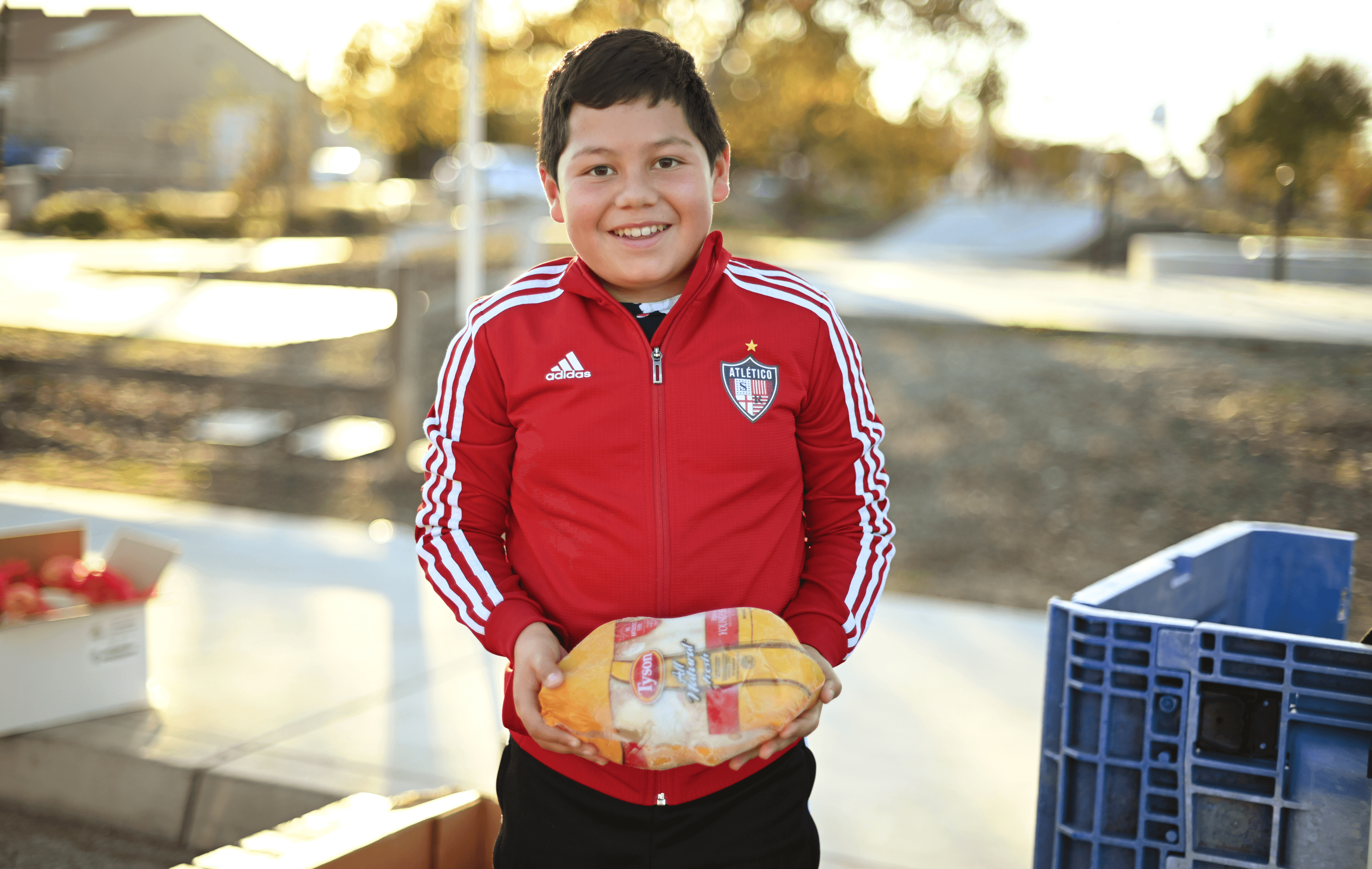A smiling boy holding a frozen chicken from a Redwood Empire Food Bank distribution.