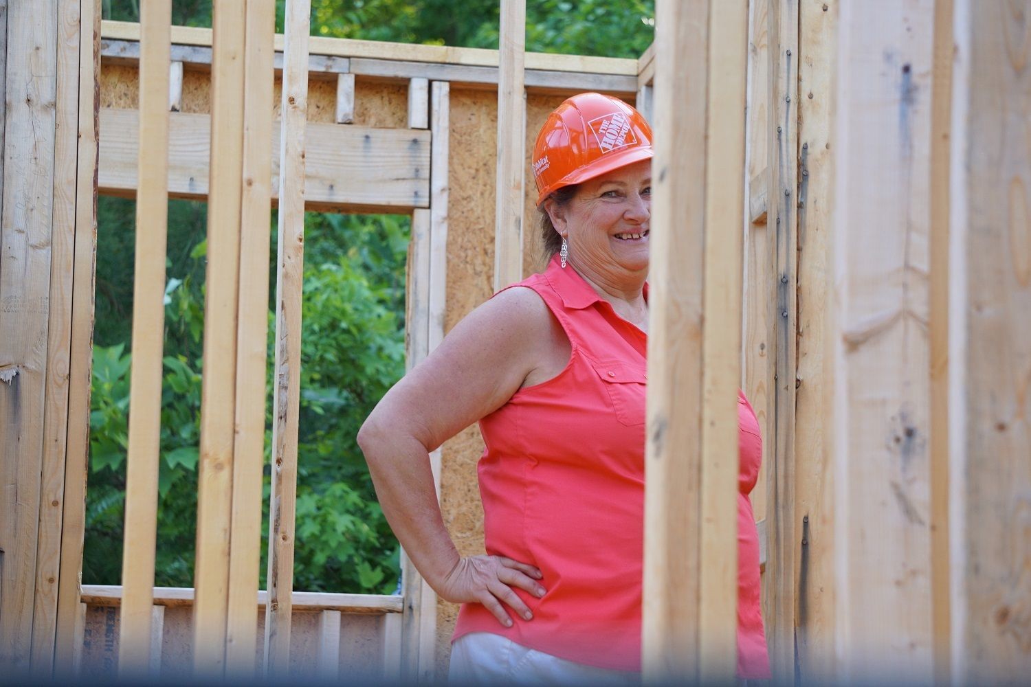 Former Executive Director and Construction Coordinator Cindy Sanders wears an orange hard hat on site of a Habitat house.