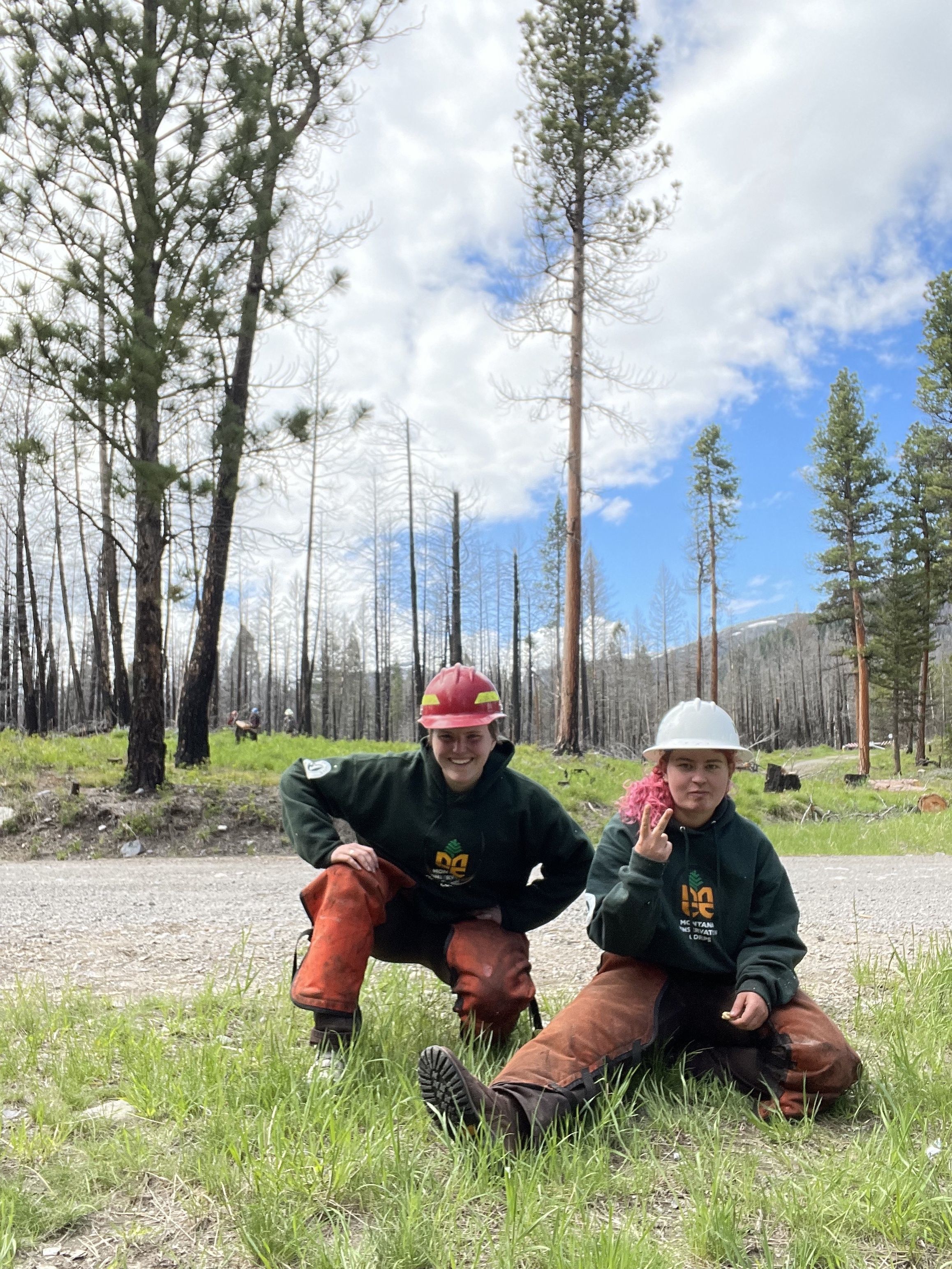 Crew leaders Emma and Mary pose in front of a road