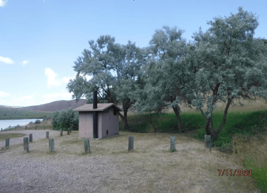 A view of a pit toilet at a campground beside a lake