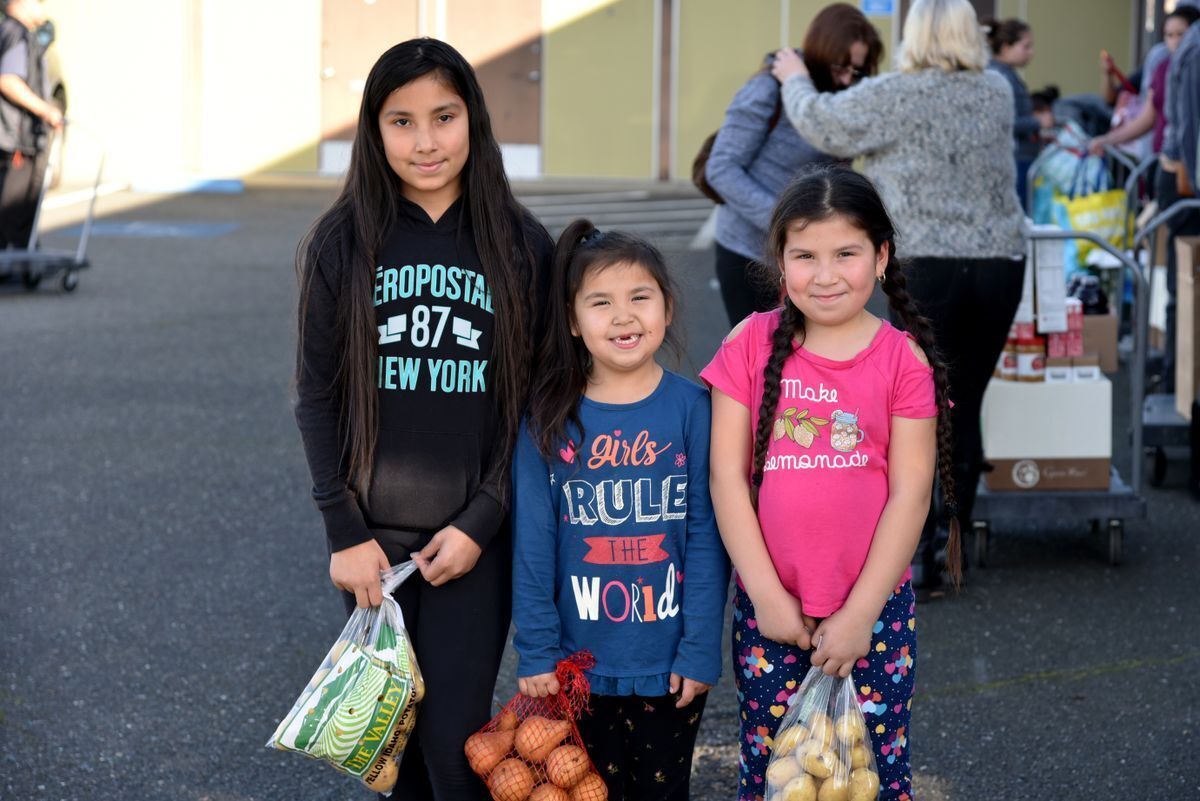 Three young children holding food from the food bank