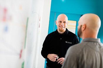 Two people chatting by a whiteboard.