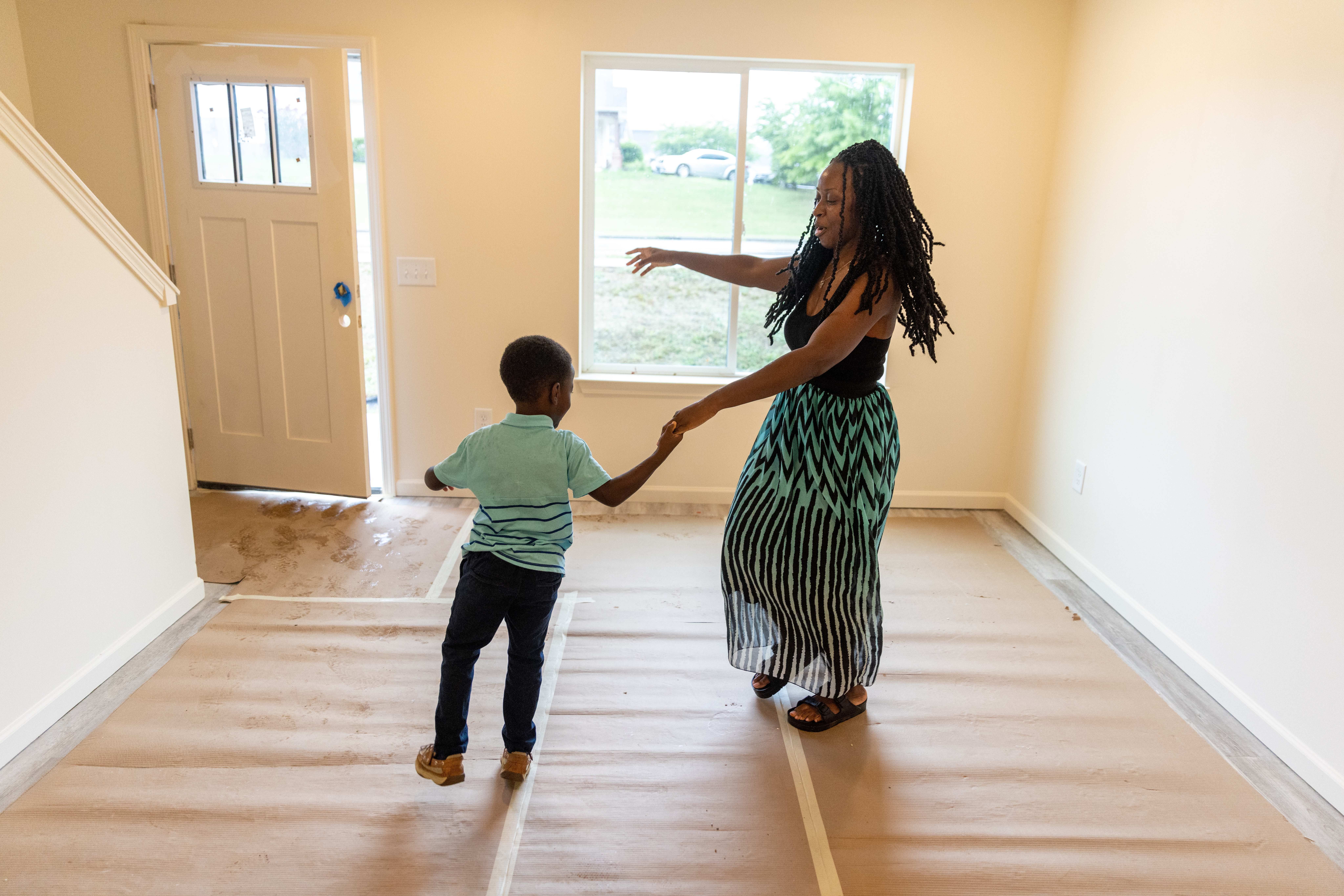 Family stands on their new porch and is being handed keys for their new home.