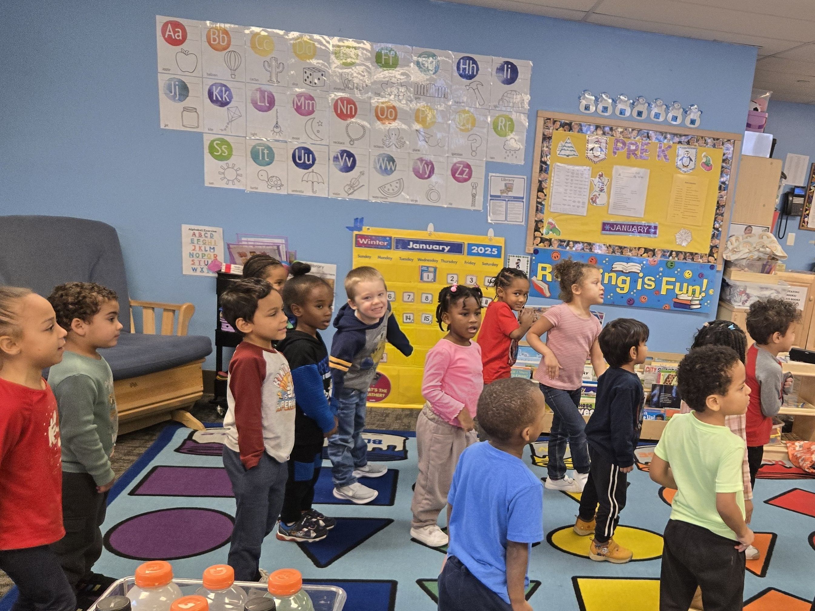 About a dozen elementary-aged students pose in their classroom for a photo with three Erie Otters hockey players, including the Erie Otters mascot.