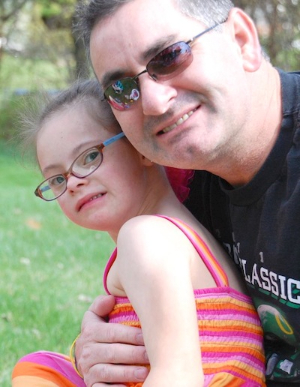 A father holding his daughter with Down syndrome.