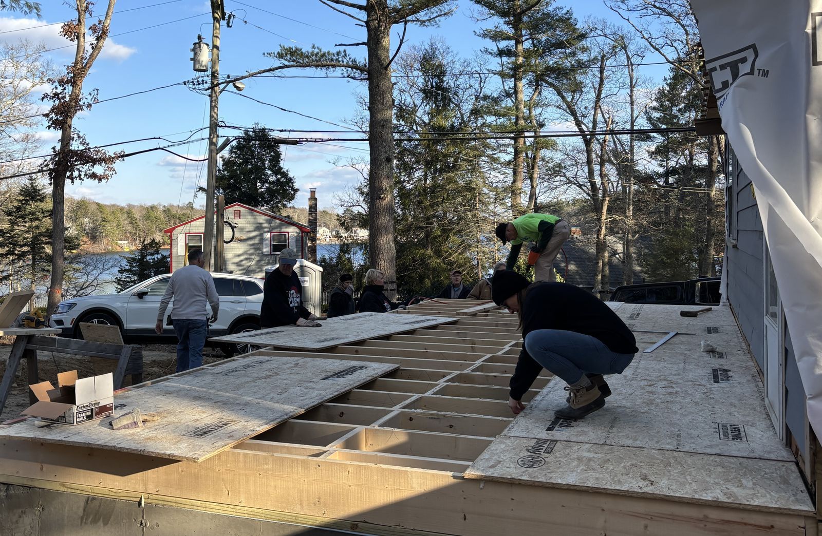 Photos of several people installing plywood flooring on new addition