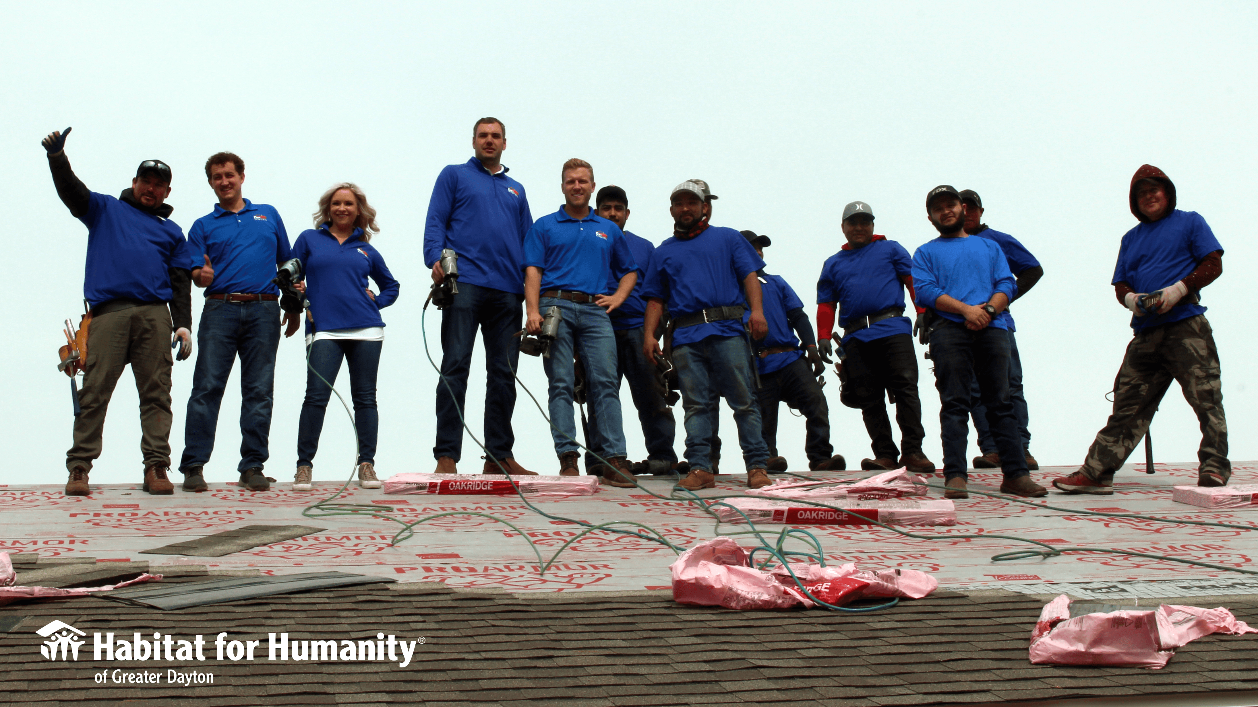 A roofing company poses on a roof while volunteering with Dayton Habitat. 