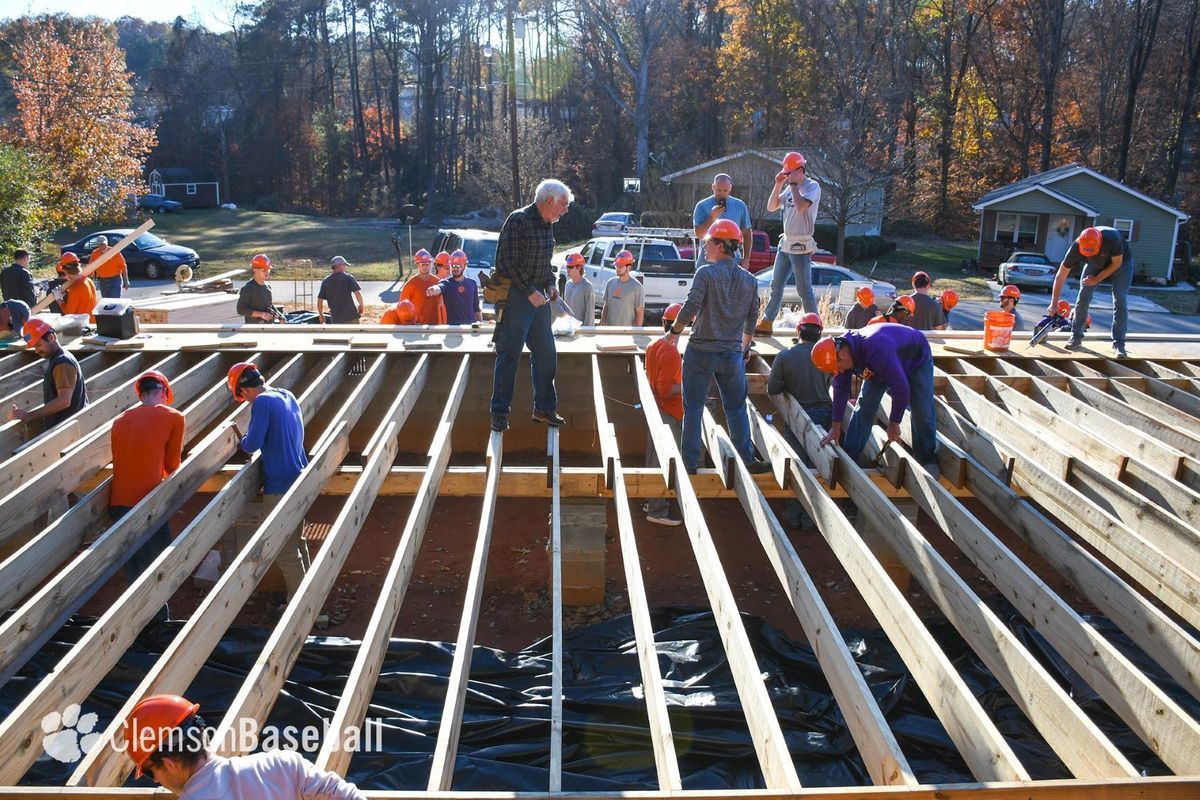 Members of Clemson University's baseball team wear orange hard hats as they build the floor joists for the Athletics Habitat home