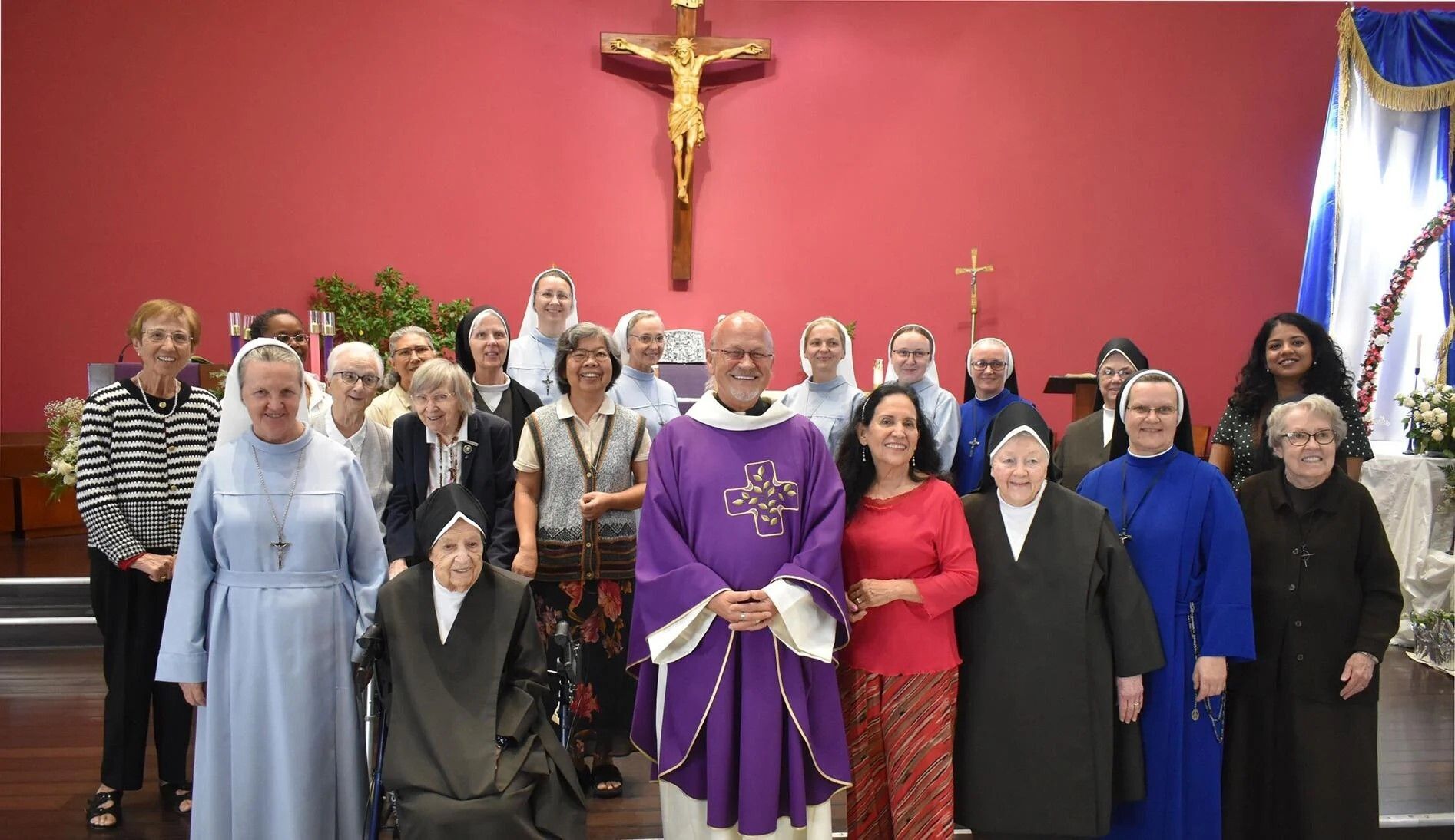 Father Andy Rudnicki and Teresa Cecil, Diocesan Council of Catholic Women president (in the red outfit), with consecrated women in the Diocese of Palm Beach in front of the altar of Mary Immaculate Church in West Palm Beach Dec. 6, 2025.