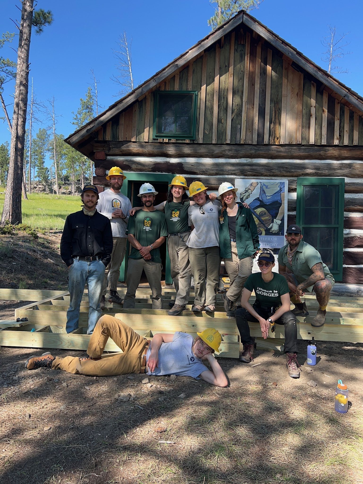 A crew stands smiling outside a USFS cabin.