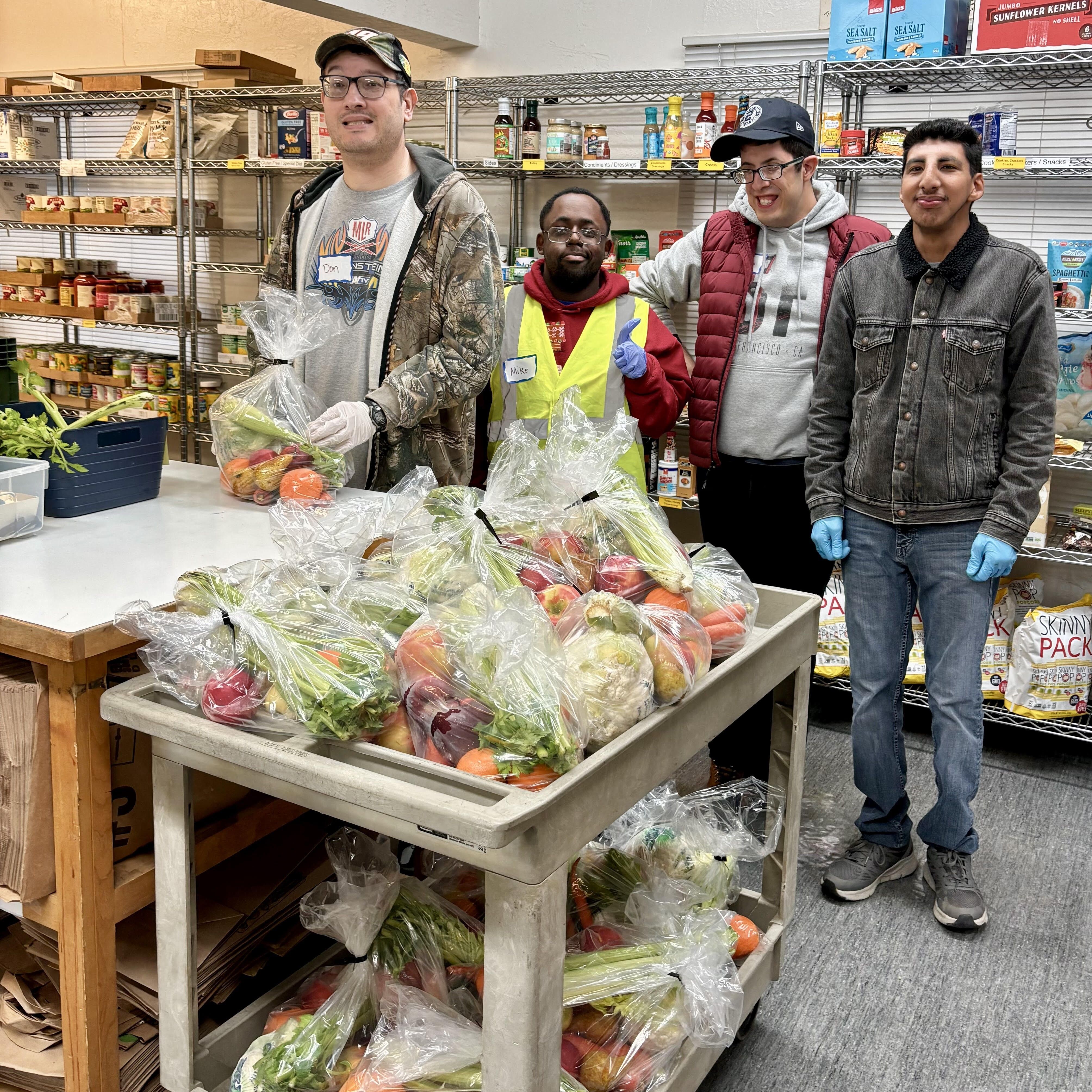 Photo of four volunteers with bags of vegetables they have packed.