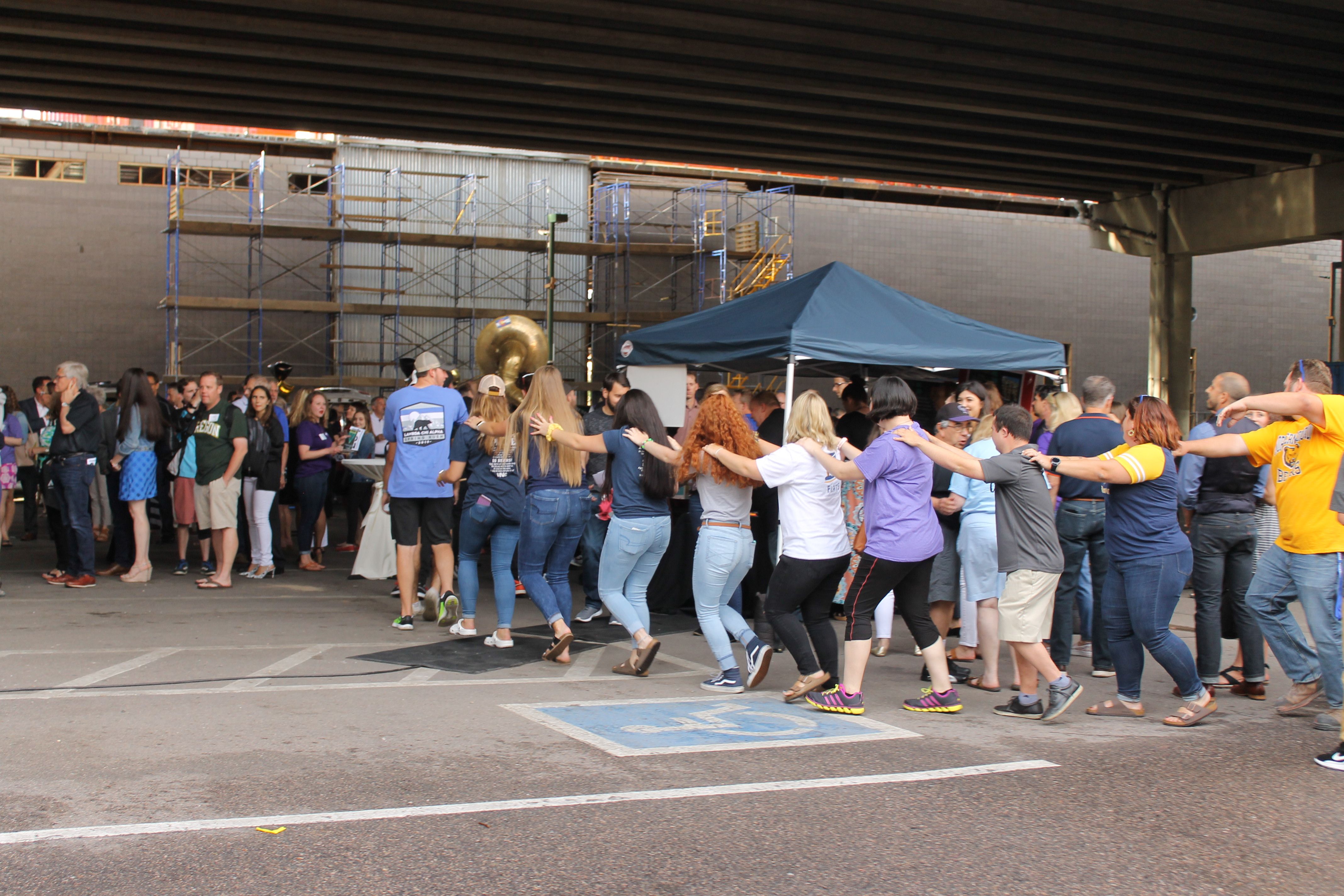 Group of people form a congo line in a parking lot