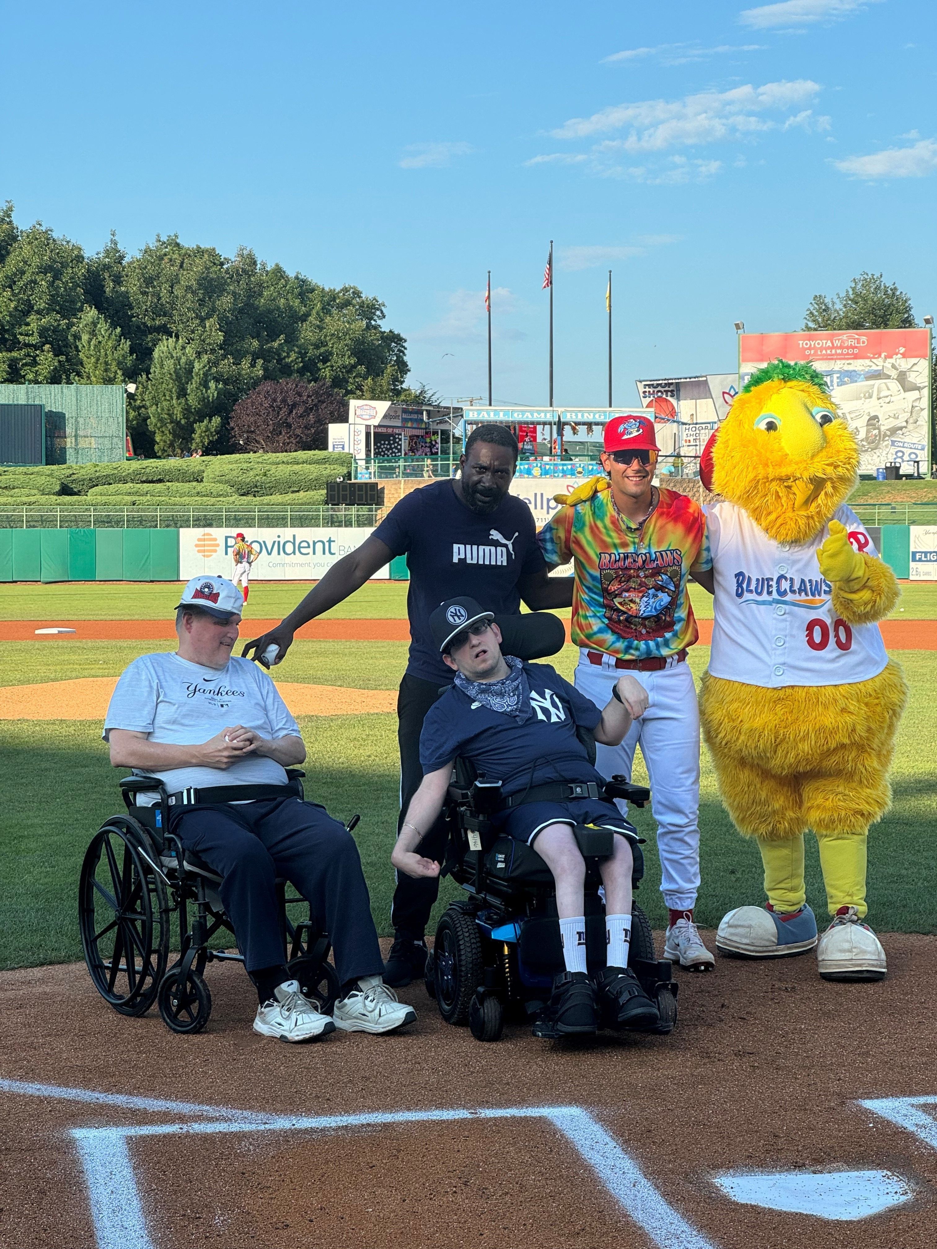 Two men in wheelchairs with a baseball player and BlueClaws mascot