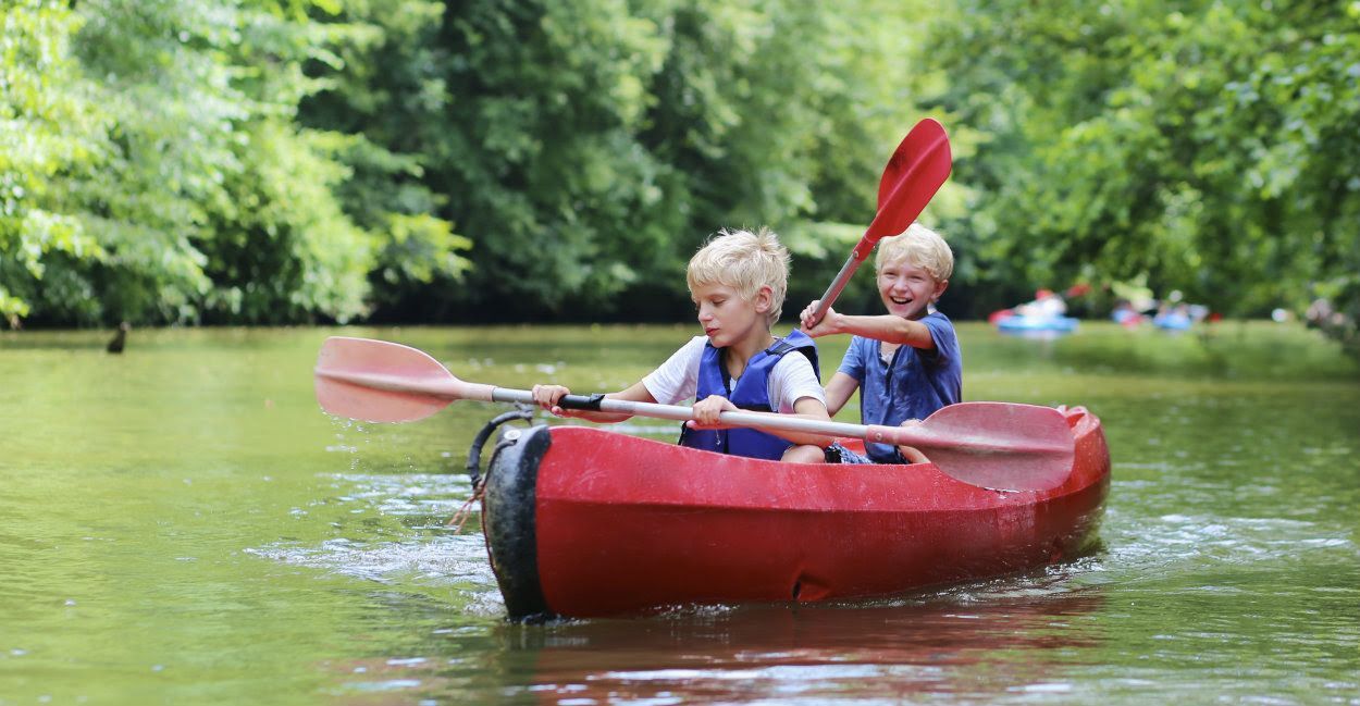 two boys paddling a canoe in a lake