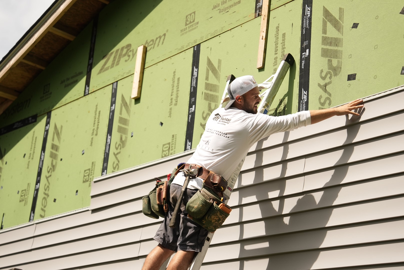 Alair Homes volunteers work to install siding on Ryan St.