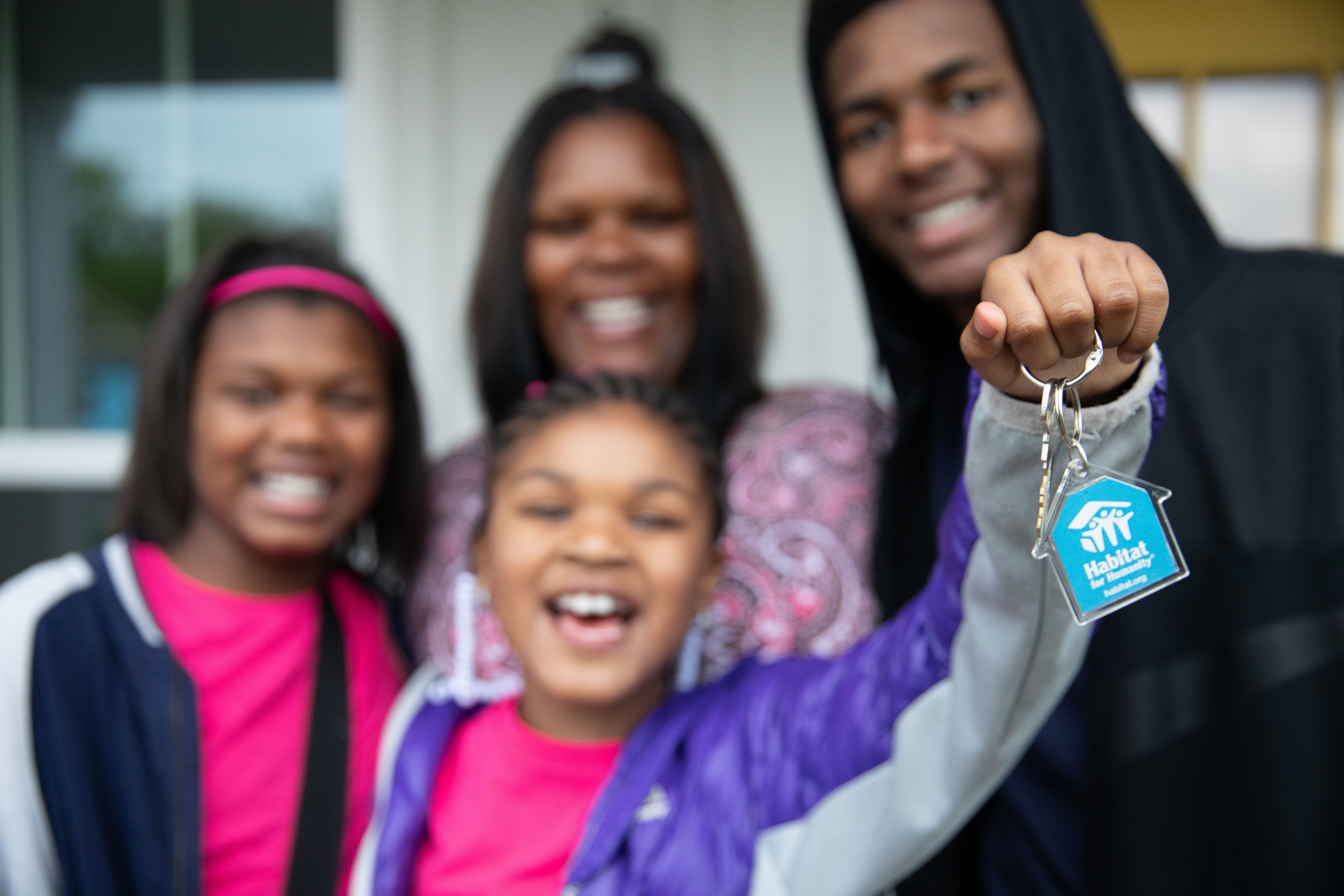 A mom, son, and two daughters hold up the keys to their new Habitat home. 