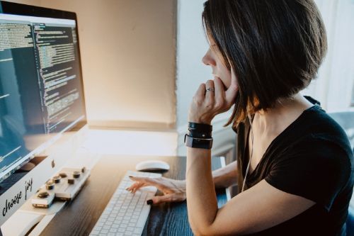 A woman gazing thoughtfully at her computer during a training.