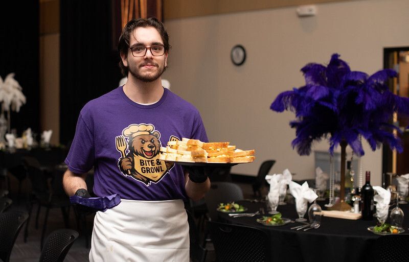 A culinary student serves hors d'oeuvres