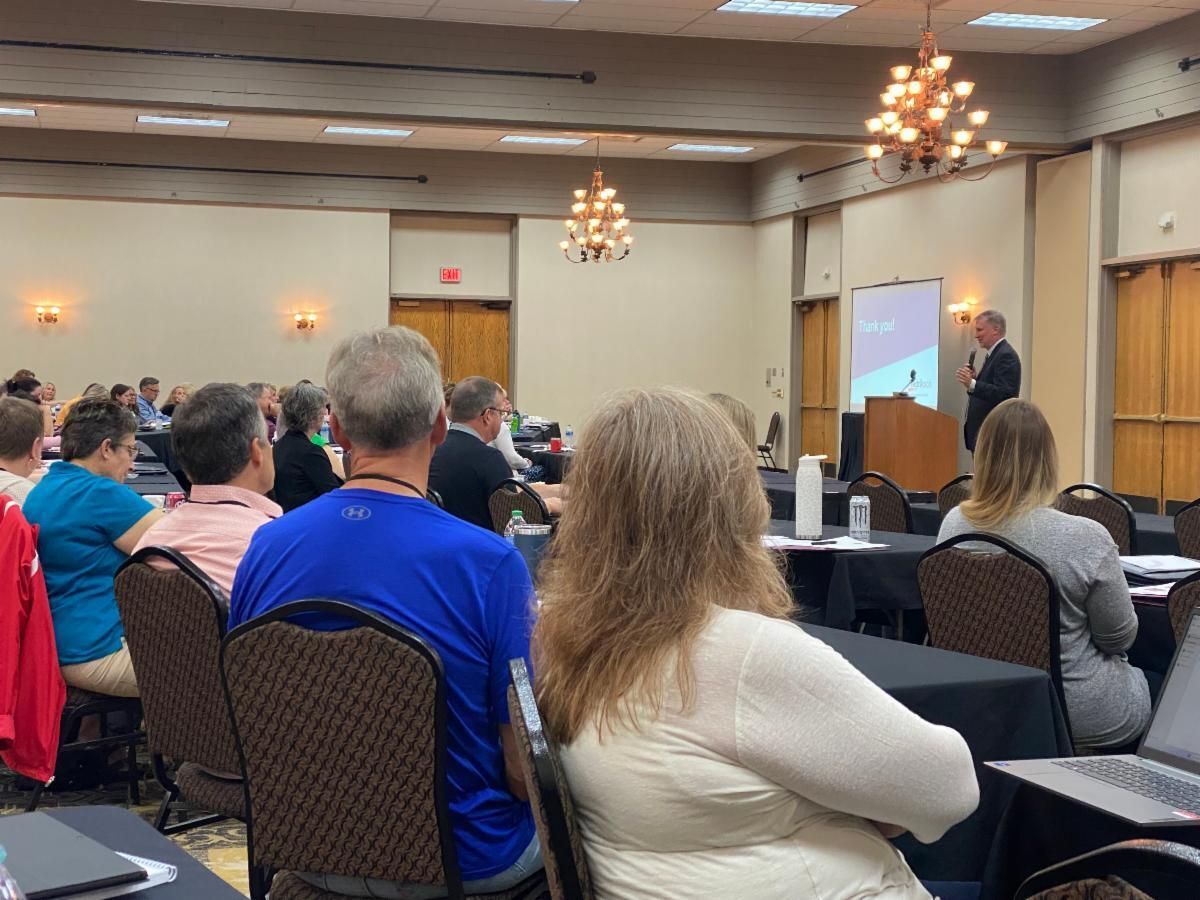 Seated crowd gathered for the Legislative Retreat, listening to a speaker's presentation.