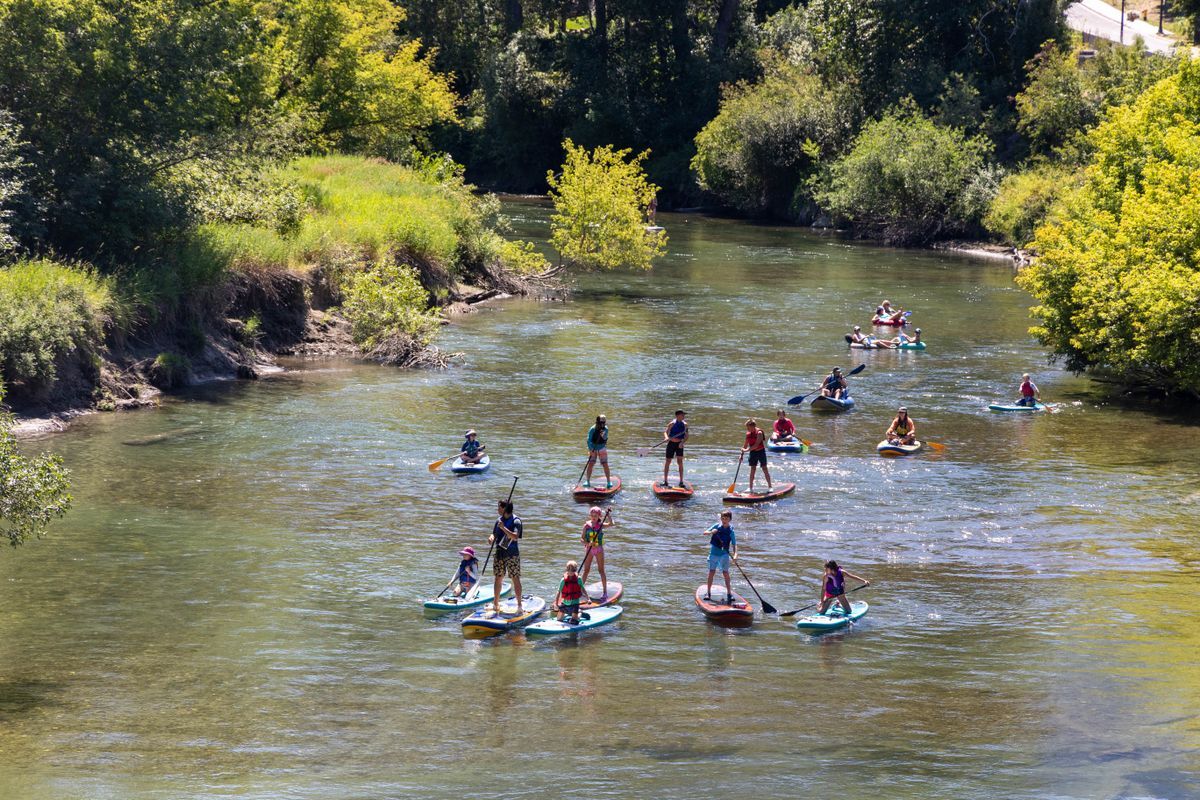 In the distance, a group of campers paddling on the river on paddle boards on the Wenatchee River.