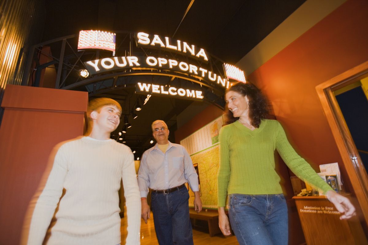 Family of three walking under a sign in the Smoky Hill Museum that says, "Salina Your Opportunity."