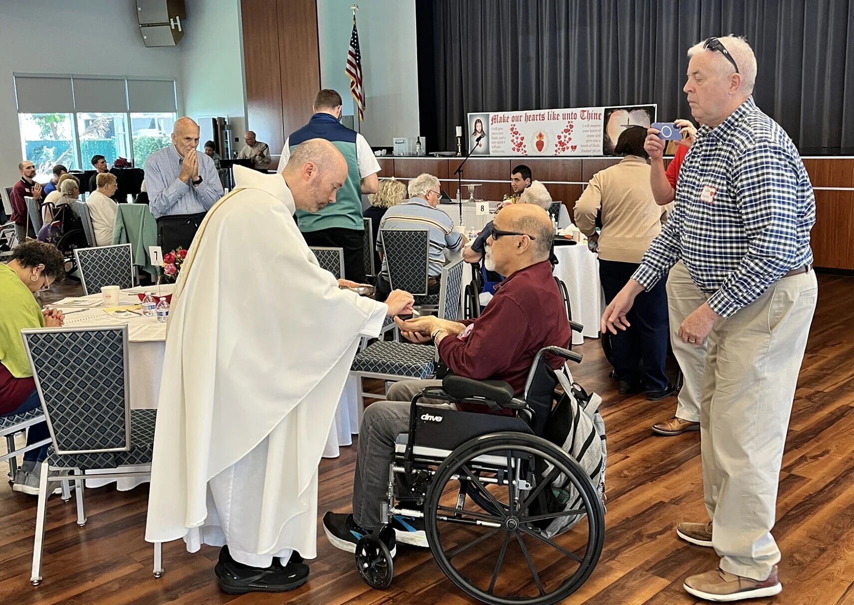 Father Kevin McQuone distributes Communion during the AIM ministry Mass in the Mercy Center at St. Joan of Arc in Boca Raton.