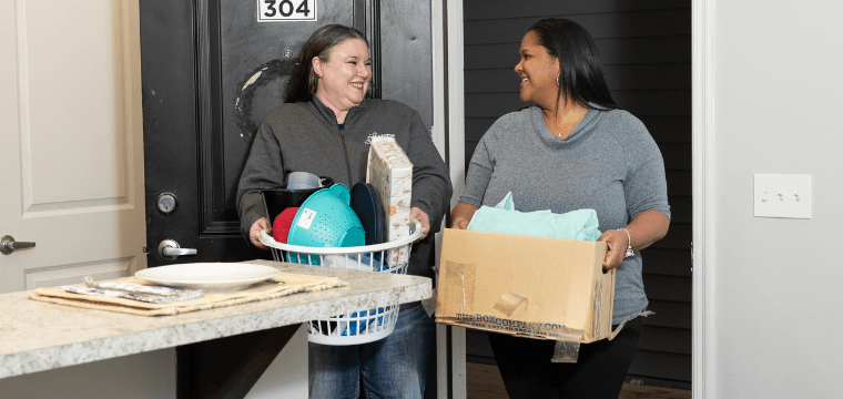 A Home for Families Case Manager with a move-in kit helps a client move into an apartment as a part of providing housing assistance.
