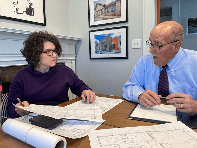 Lura Godfrey sits at a table reviewing house plans with her father, PCHFH Board Member Bob DiAntonio