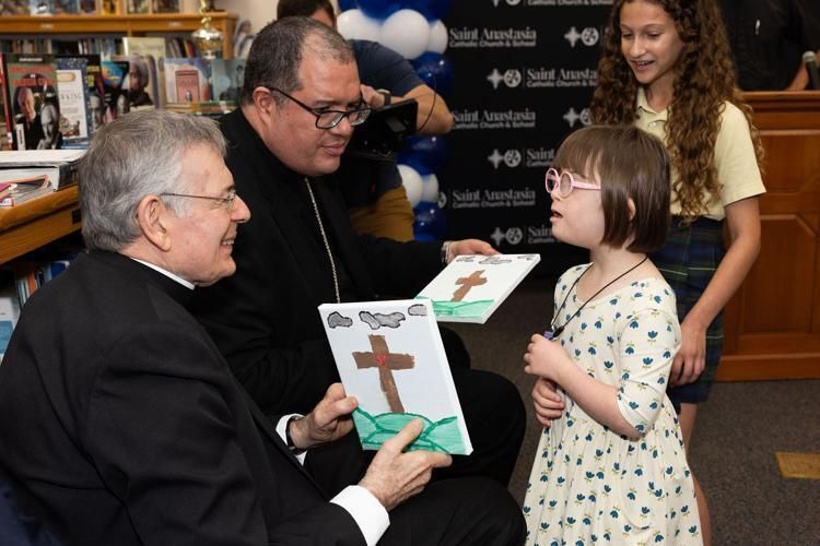 Bishop Emeritus Gerald M. Barbarito, left, and Bishop Manuel de Jesús Rodríguez interact with a girl who is enrolled in the morning star program at St. Anastasia School in Fort Pierce.